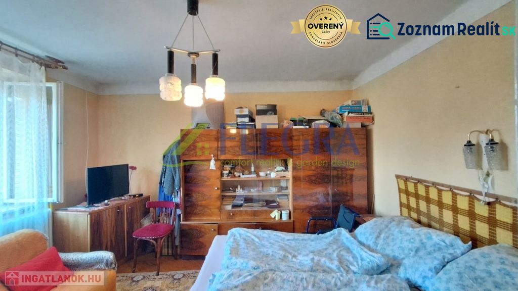 Ein Zimmer in einem Einfamilienhaus mit Möbeln, einem Bett und einem Fernseher, einfaches Interieur.