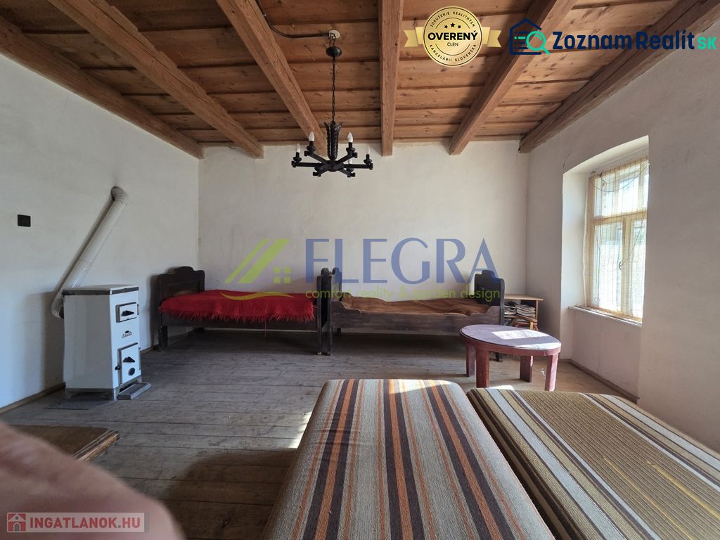 Ein Zimmer in einem Einfamilienhaus mit Holzbalkendecke und Kachelofen.