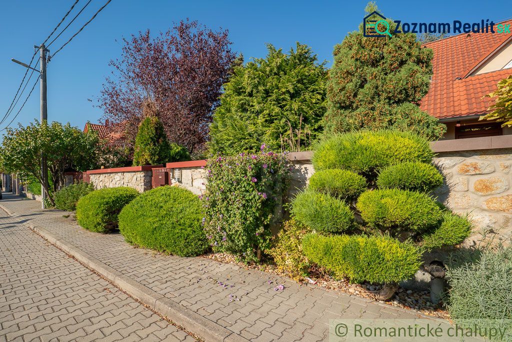 Ein Einfamilienhaus in Bernolákovo mit einem gepflegten Garten und einer Steinmauer.
