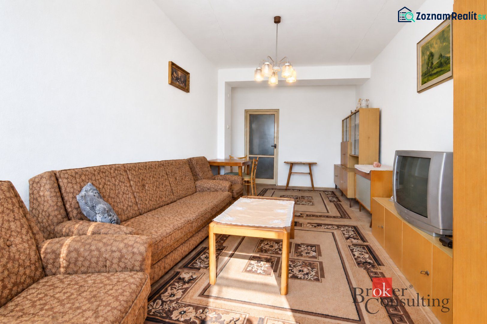 Wohnzimmer mit braunem Sofa, Couchtisch und Fernseher in einer Zweizimmerwohnung.