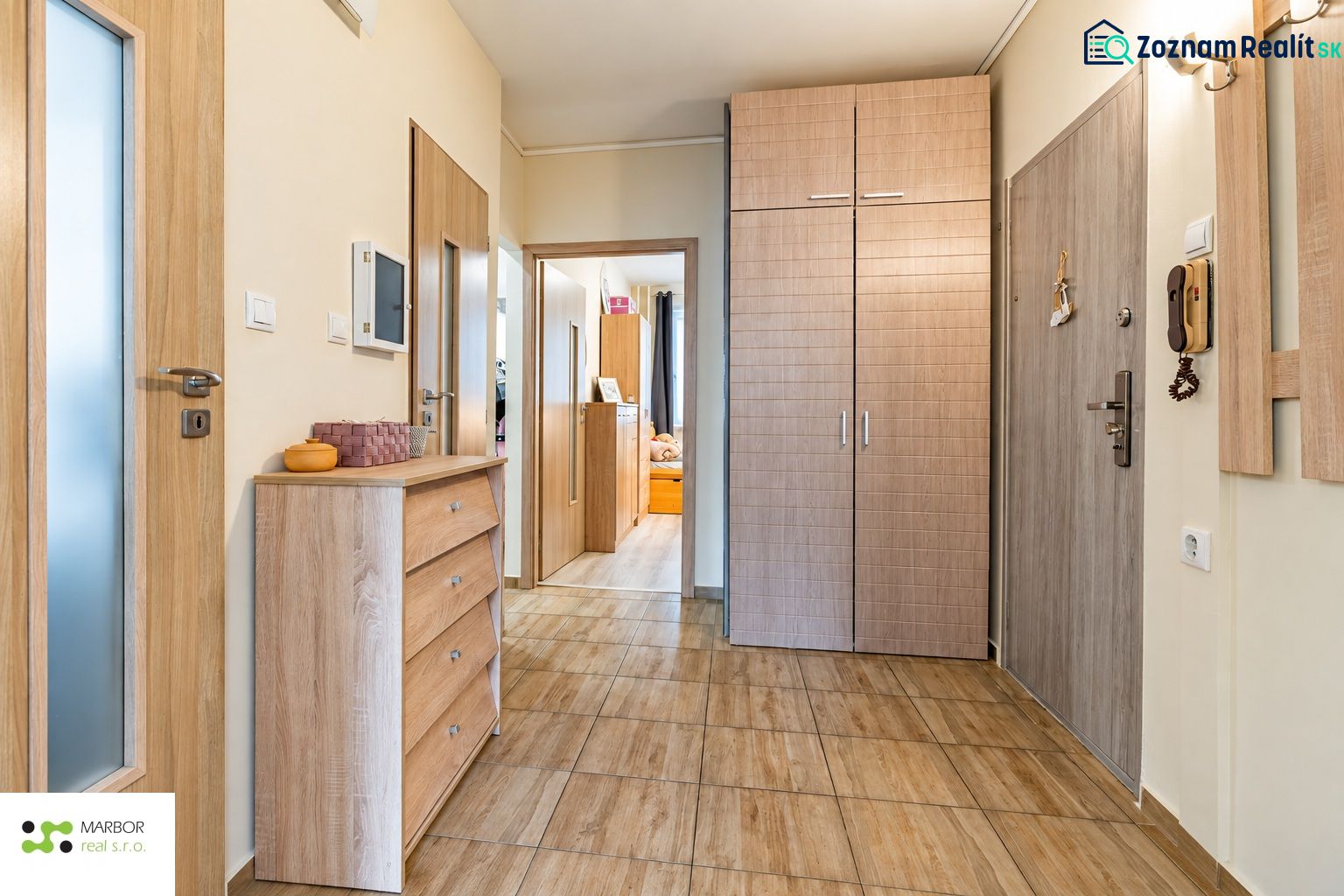 Eingangsbereich in einer 3-Zimmer-Wohnung, helle Holztüren und Boden mit Holzdekor.