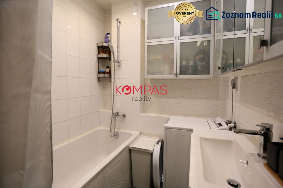 Badezimmer in einer 2-Zimmer-Wohnung mit Badewanne, Schränken und Waschmaschine.
