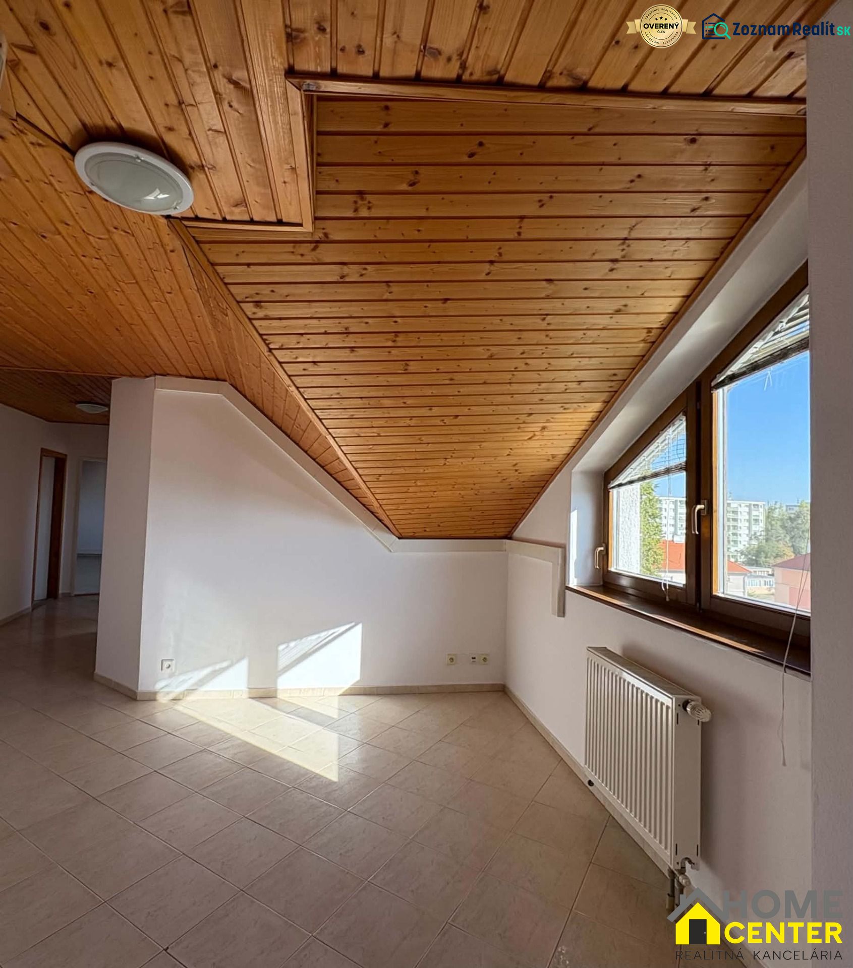 3-Zimmer-Wohnung mit Holzbalkendecke, Fliesenboden, Licht, das durch ein großes Fenster dringt.