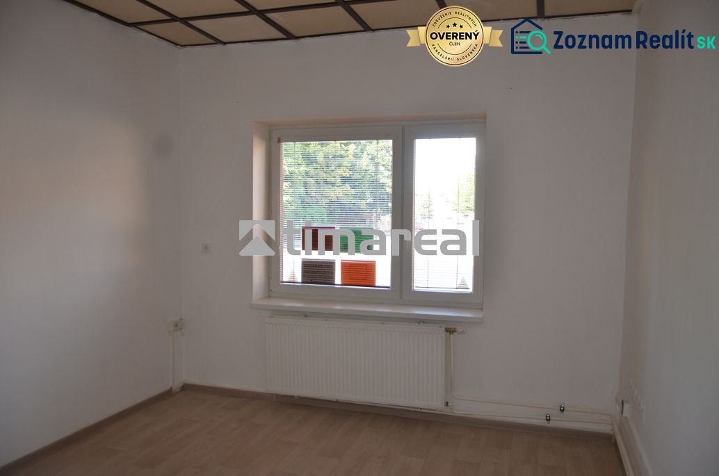 Büros mit weißen Wänden und einem Boden in Holzoptik, ein Fenster mit Heizkörper ist zu sehen.