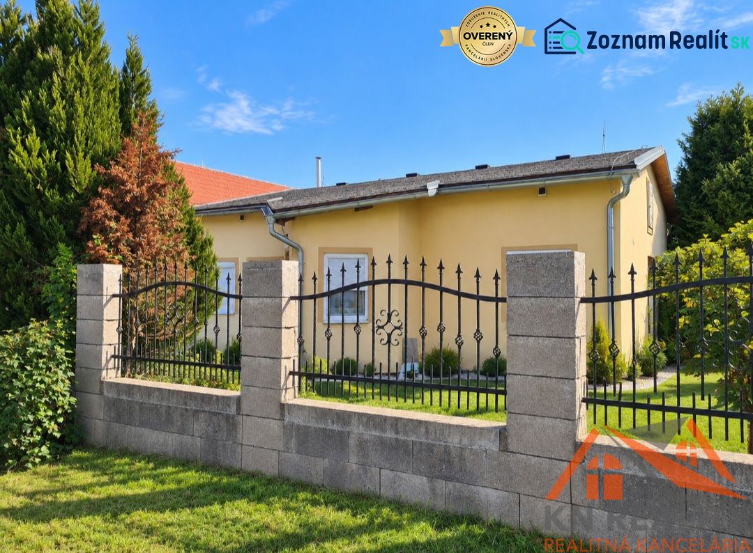 Ein Einfamilienhaus in Martovce mit einem Garten, umgeben von grünen Bäumen und einem Zaun.