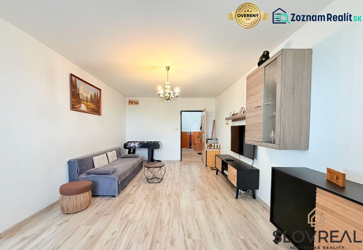 Wohnzimmer in einer 3-Zimmer-Wohnung mit Holzboden, grauem Sofa und Tischfußball.