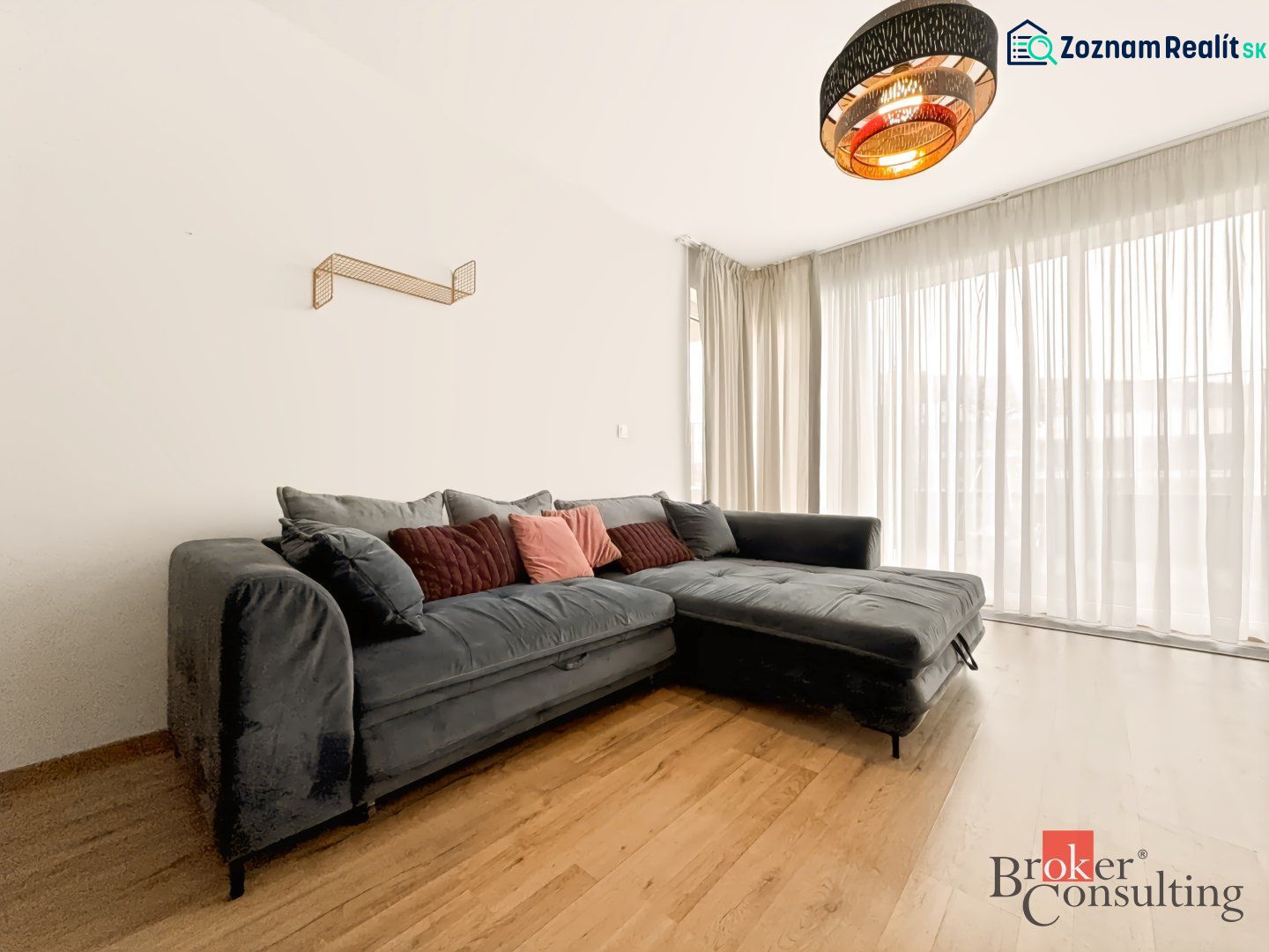 Wohnzimmer in einer 2-Zimmer-Wohnung mit einer Eckcouch und einem Boden in Holzoptik.