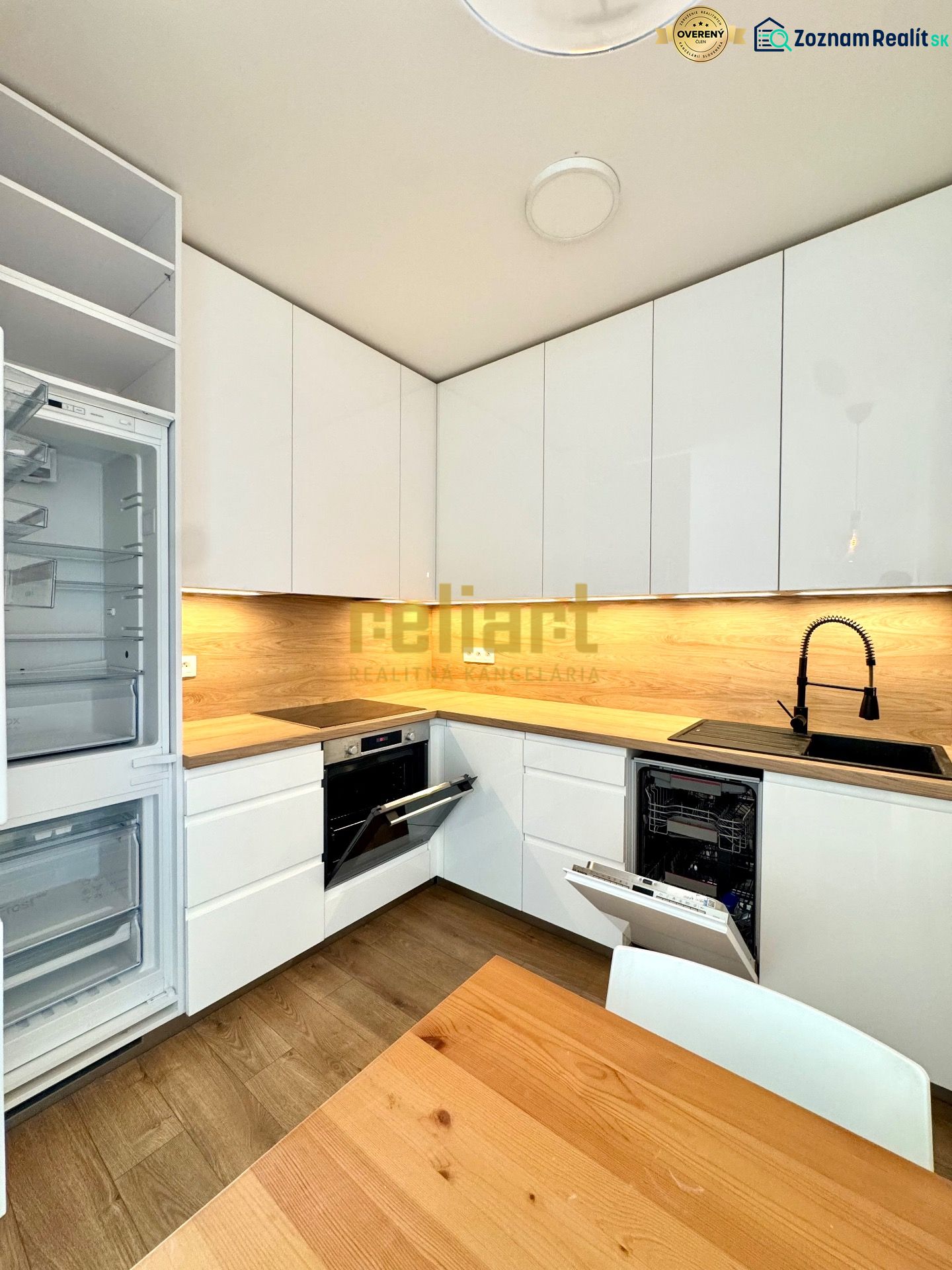 Küche in einer 2-Zimmer-Wohnung mit weißen Schränken und Holzboden-Dekor.