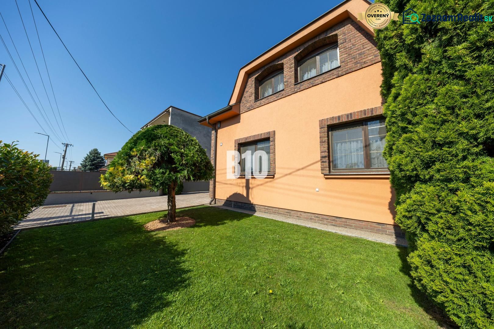 Ein Einfamilienhaus in der Bratislavská-Straße in Malinovo mit einem gepflegten Garten und einem Baum.