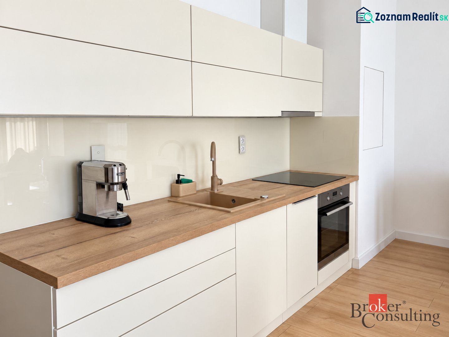 Küche in einer Einzimmerwohnung mit Holzdekorboden, cremefarbene Schränke, Kaffeemaschine.
