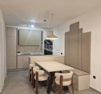 Esszimmer in einer Ferienwohnung mit Küche, hellen Stühlen und grauen Wandpaneelen.