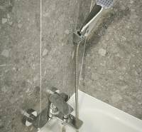 Duscharmatur im Badezimmer mit grauen Fliesen im Einzimmerapartment.