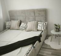 Einzimmerwohnung mit Bett und Nachttisch auf hellem Boden, geschmackvolle Dekoration.