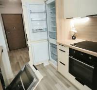 Küche in einem Studio-Apartment mit offenen Geräten und hellem Holz auf dem Boden.