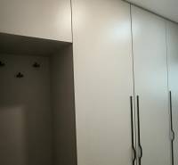 Weiße Schränke mit vertikalen Griffen im Einzimmerapartment.
