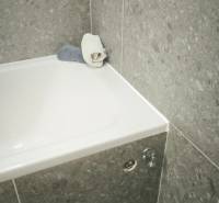 Badezimmer mit Badewanne und grauen Fliesen, geeignet für ein Studio-Apartment.