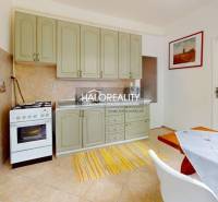 Küche einer 4-Zimmer-Wohnung mit hellen Schränken, Esstisch und Backofen.