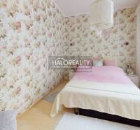 Schlafzimmer in einer 4-Zimmer-Wohnung mit Blumen-Tapeten und Bett.
