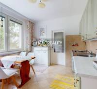 Küche in einer 4-Zimmer-Wohnung mit Holztisch, Stühlen und einem großen Fenster mit Vorhang.