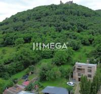 Ein Blick auf ein Einfamilienhaus in Brekov, umgeben von Grün und einem Hügel mit einer Burg.