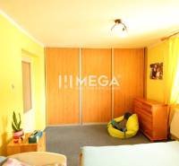 Ein gelbes Zimmer in einem Einfamilienhaus mit einem Bett, einem Schränkchen und einem Sitzsack.