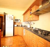 Küche in einem Einfamilienhaus mit Holzschränken, Herd, Mikrowelle und Kühlschrank.