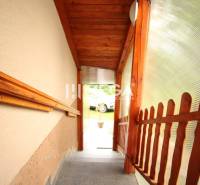 Treppe mit Holzgeländer, die ins Freie eines Einfamilienhauses führt.