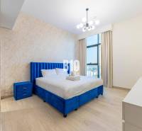 Schlafzimmer in einer 3-Zimmer-Wohnung mit blauem Bett, Kommode und moderner Beleuchtung.