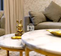 Goldene Hasenstatue auf einem Marmortisch in einer 3-Zimmer-Wohnung mit einem bequemen grauen Sofa.