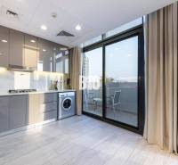 Küche in einer 3-Zimmer-Wohnung mit Waschmaschine und Balkon, helle Schränke, großes Fenster.