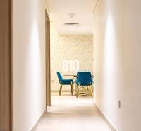 Der Flur führt in ein Zimmer mit blauen Stühlen und einer gemusterten Wand in einer 3-Zimmer-Wohnung.