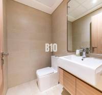 Badezimmer in einer 3-Zimmer-Wohnung mit hellen Fliesen, Spiegel und Waschbecken.