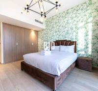 Schönes Schlafzimmer in einer 3-Zimmer-Wohnung mit Bett, botanischer Tapete und Holzschrank.