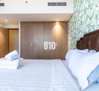 Schlafzimmer mit Doppelbett, Holzschrank und geblümter Tapete in einer 3-Zimmer-Wohnung.