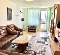 Wohnzimmer in einer 3-Zimmer-Wohnung mit einem braunen Sofa und Holzmöbeln.