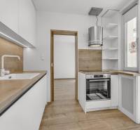 Küche mit Holzelementen und eingebauten Geräten in einer 4-Zimmer-Wohnung.