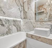 Ein Badezimmer in einer 4-Zimmer-Wohnung mit einer Badewanne und einem Waschbecken, umgeben von Marmorfliesen.