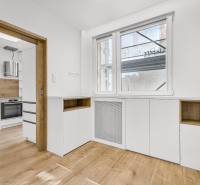 Küche einer 4-Zimmer-Wohnung mit Holzboden und weißen Schränken.