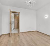 Ein leerer Raum mit Holzboden und einem Kronleuchter in einer Vierzimmerwohnung.