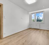 Ein leerer Raum mit Holzboden und Kunststofffenster in einer 4-Zimmer-Wohnung.