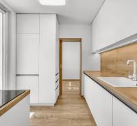 Küche in einer 4-Zimmer-Wohnung mit weißen Schränken und einer Holzarbeitsplatte.