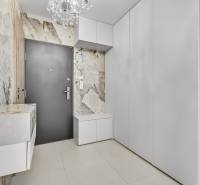 Diele einer 4-Zimmer-Wohnung mit weißen Möbeln, strukturierten Wänden und einem Kronleuchter.