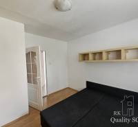 Schlafzimmer in einer 2-Zimmer-Wohnung mit Bett, Schrank und offener Tür, die in den Flur führt.