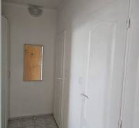 Flur mit Spiegel in einer 2-Zimmer-Wohnung, weiße Wände und Türen, Fliesenboden.