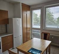 Küche mit Esstisch, Kühlschrank und Schränken in einer 2-Zimmer-Wohnung.