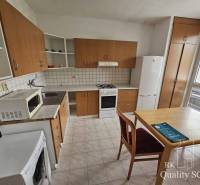 Küche in einer 2-Zimmer-Wohnung mit Holzschränken und Esstisch.