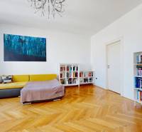 Wohnzimmer in einer 3-Zimmer-Wohnung mit Sofa, Bücherregal, Bild und Holzboden.