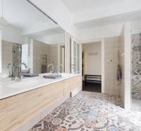 Badezimmer mit Doppelwaschbecken, Duschkabine und gemusterten Fliesen in einer 3-Zimmer-Wohnung.