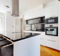 Küche in einer 3-Zimmer-Wohnung mit Insel, weißen Schränken und eingebauten Geräten.