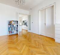 Ein geräumiges Zimmer in einer 3-Zimmer-Wohnung mit Bibliothek, Parkettboden und weißen Türen.